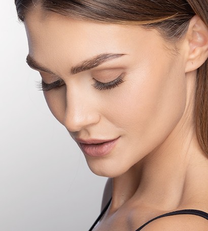 下を向いて微笑むモデル。眉毛とまつ毛を強調します。